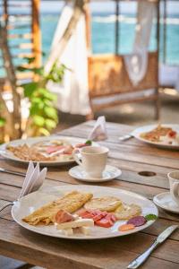einen Tisch mit Teller mit Speisen und Tassen Kaffee in der Unterkunft Mangata Beach in Cartagena de Indias