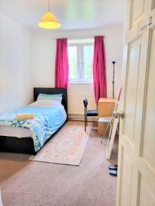 Schlafzimmer mit einem Bett und einem Fenster mit rosa Vorhängen in der Unterkunft London Rooms in London
