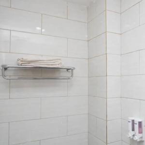 a white tiled bathroom with towels on a towel rack at Capital Hotel Makassar in Pampang