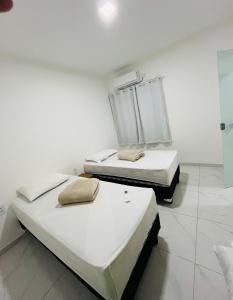 two beds in a room with white walls at NOVO APARTAMENTO Liz 1 in Porto Seguro