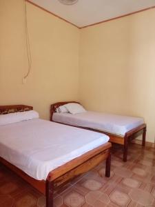 dwa łóżka w pokoju z białą pościelą w obiekcie Ocean Holiday liukang w mieście Bira