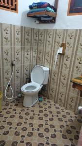 a bathroom with a toilet and a tiled floor at Ocean Holiday liukang in Bira