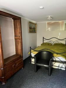 a bedroom with a bed and a black chair at Huriana Place in Kaitaia