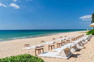 a row of chairs on a beach with the ocean at Santhiya Phuket Natai Resort & Spa in Natai Beach