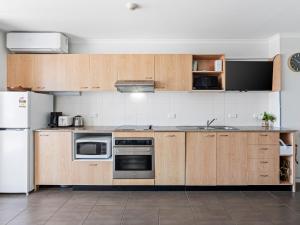 a kitchen with wooden cabinets and stainless steel appliances at Nesuto Apartments - Unit 532 in The Entrance +1 photo