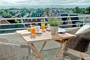 einen Holztisch mit zwei Gläsern Orangensaft auf dem Balkon in der Unterkunft Haus Norderhoog Wohnung 67 - "Zoe's Nest"  in Westerland