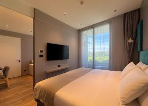 a bedroom with a large bed and a television at La Green Hotel and Residence in Bang Tao Beach