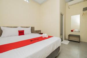 um quarto com uma grande cama branca e um cobertor vermelho em RedDoorz @ Sangnala Homestay Pakisaji em Malang