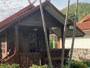 a wooden house with a porch and a balcony at สวนดวงมณี รีสอร์ท in Ban Tha Thong Mon