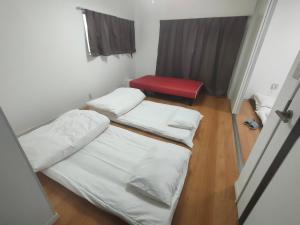 Zimmer mit 3 Betten und einem roten Stuhl in der Unterkunft 佐世保　貸切小さな一軒家　GUEST HOUSE　楽楽 Luck-Luck in Sasebo