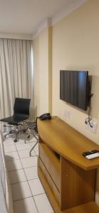 Habitación de hotel con escritorio y TV en la pared en PONTA NEGRA FLAT, en Natal