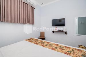 um quarto com uma cama e uma televisão na parede em Swun Stay Inn At Sawahan Mitra RedDoorz em Malang