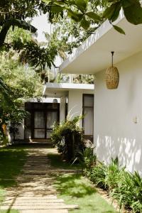 a white house with a pathway leading to the front yard at The Nuga House in Ahangama