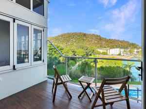 two chairs on a balcony with a view of a mountain at Waterfront Townhouse 'Beachside Apartment 16' - Central location, pool, good wifi in Nelly Bay