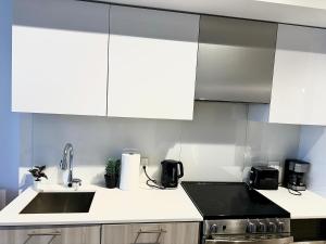 a kitchen with white cabinets and a sink at Cozy 2 Bedroom by Eaton Centre Mall in Toronto