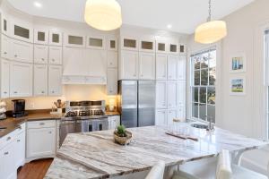 a kitchen with white cabinets and a marble counter top at Coastal Cottage with Pool - Restoring Galveston in Galveston