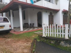 uma casa branca com uma cerca à frente. em Kandy ambuluwawa mount villa em Angammana