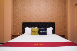 a bedroom with a large bed with two pillows on it at Urbanview Hotel L'Tefa Pemalang 