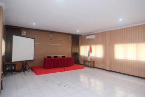 a large room with a red couch and a screen at Urbanview Hotel L'Tefa Pemalang 