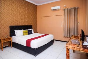 a bedroom with a large bed and a desk at Urbanview Hotel L'Tefa Pemalang 