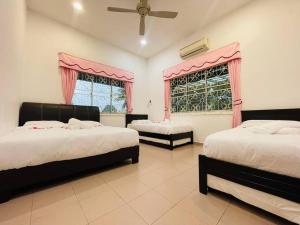 een slaapkamer met 2 bedden en een raam met roze gordijnen bij GreenPine Kota Tinggi Homestay in Kota Tinggi