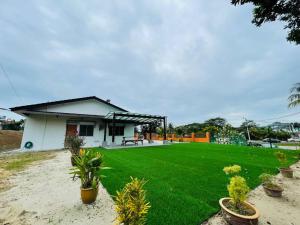 een klein huis met een groen gazon ervoor bij GreenPine Kota Tinggi Homestay in Kota Tinggi