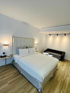 a bedroom with a large white bed and wooden floors at TY Motel in Dayuan