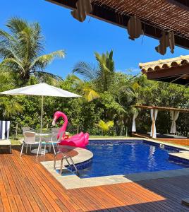 einen Pool mit einem rosa Flamingo, einem Tisch und einem Sonnenschirm in der Unterkunft Costa do Sauipe Casa dentro do complexo hoteleiro in Costa do Sauipe