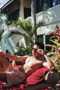 a shirtless man in a swimsuit and sunglasses laying on a towel at Villa Maly Boutique Hotel in Luang Prabang