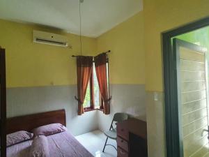 a bedroom with a bed and a window and a desk at OYO 93444 Damia Homestay Syariah in Surabaya