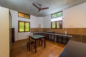 a kitchen with a table and a ceiling fan at Aurovidya Retreat in Kottakupam +37 photos