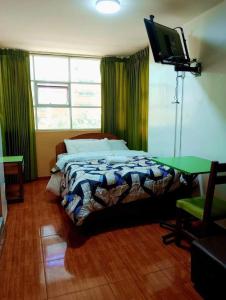 a bedroom with a bed and a flat screen tv at Sierra Verde - Muy Céntrico Hs in Huancayo