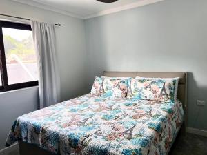 - une chambre avec un lit avec une couette à fleurs et une fenêtre dans l'établissement Mirah's Villa & Apartments, 