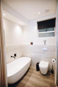 uma casa de banho com uma banheira branca e um WC. em Beachfront Luxury Family Escape em Cidade do Cabo