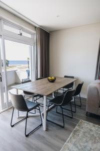 uma sala de jantar com mesa e cadeiras e o oceano em Beachfront Luxury Family Escape em Cidade do Cabo
