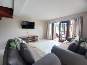 a living room with a couch and a television at Modern two bedroom apartment. in Port Alfred