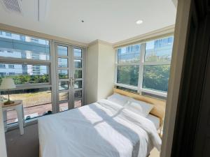- une chambre avec un lit blanc et de grandes fenêtres dans l'établissement Busan Centurn Victoria hotel, à Busan