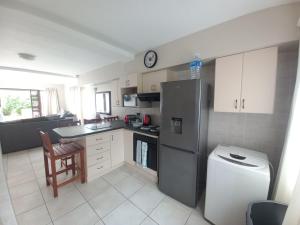 eine Küche mit einem Kühlschrank, einer Spüle und einem Tisch in der Unterkunft Modern two bedroom apartment. in Port Alfred
