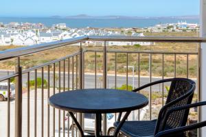 a table and chairs on a balcony with a view of the ocean at Nivica 46 Luxury Apartment Langebaan in Langebaan