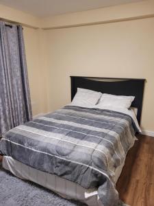 a bedroom with a bed with a blue and gray blanket at Silverbuttons Apartments & Eats in Dickenson Bay
