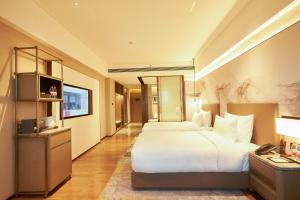 um quarto de hotel com uma cama grande e uma televisão em LN Dongfang Hotel, Pazhou em Guangzhou
