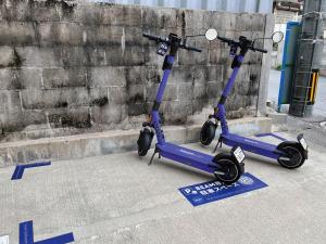 duas scooters azuis estacionadas ao lado de uma parede em Condominium L's INN em Naha