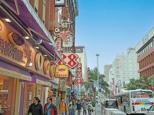 een drukke straat met mensen die over straat lopen bij Condominium L's INN in Naha