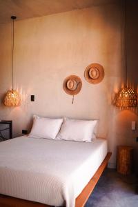a bedroom with a white bed with two baskets on the wall at Baja Temple in Todos Santos