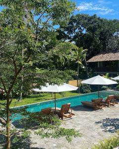 een zwembad met stoelen en parasols naast een resort bij Maison Samara in Hikkaduwa