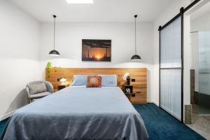 a bedroom with a large bed and a chair at The Electric Hotel in Geelong