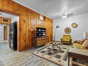 ein Wohnzimmer mit holzgetäfelten Wänden und einem TV in der Unterkunft 1br Residence With Vast Backyard in Des Moines