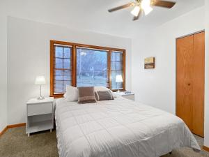 a white bedroom with a bed and two windows at 3bed Cozy House In Quiet Neighborhood in Des Moines