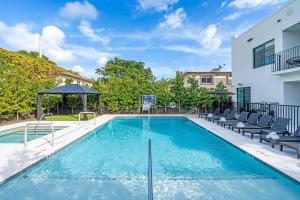 a swimming pool with chairs and a building at Lux Retreat By Renzzi in Miami