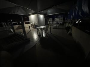 Cette chambre sombre comprend une table, des chaises et un parasol. dans l'établissement HOTEL 229 42, à Cotonou